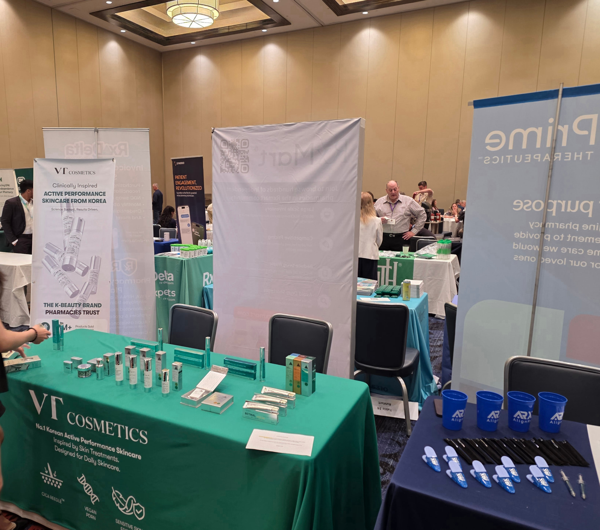 VT Cosmetics exhibit with green tablecloth, skincare products and banner at a pharmacy convention